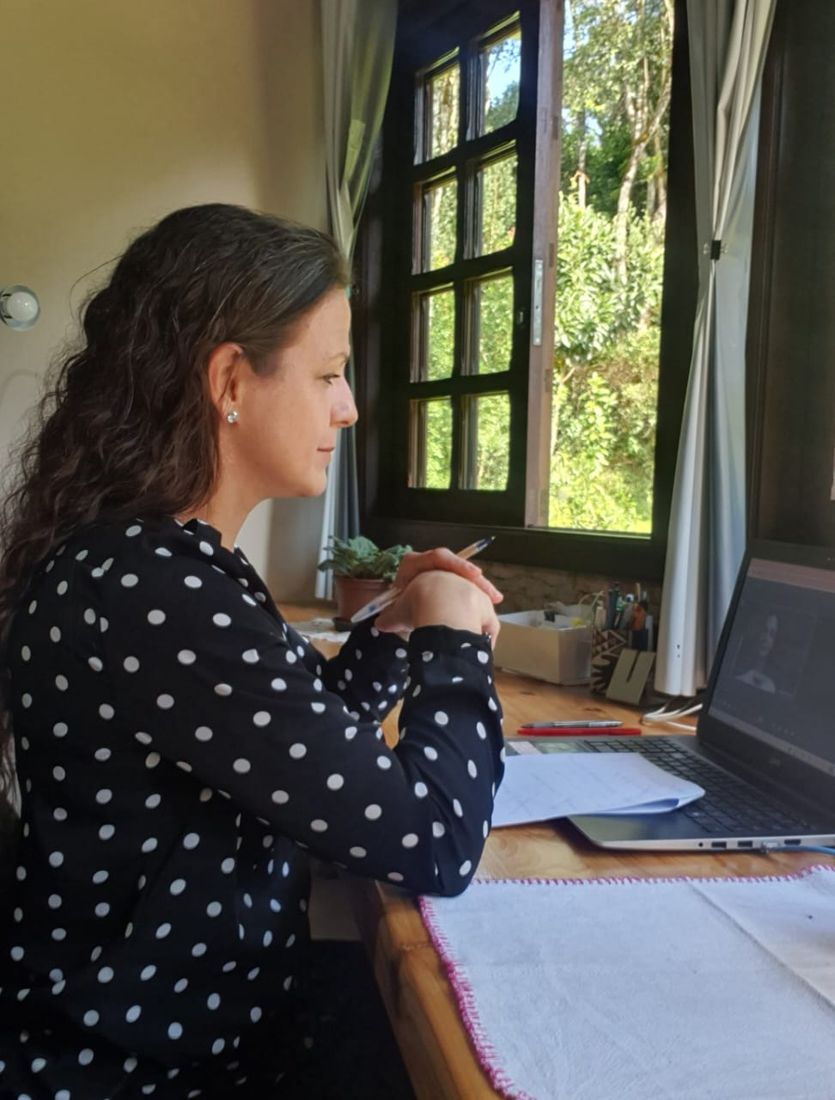 Dra. Maria Angélica em atendimento online, à mesa diante do computador